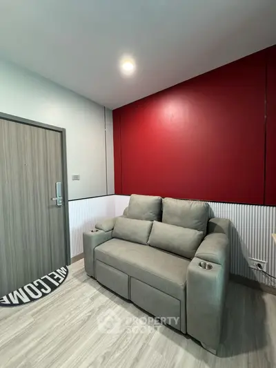 Modern living room with stylish red accent wall and cozy gray sofa.