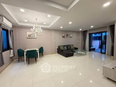 Spacious modern living room with elegant chandelier and large windows for natural light.