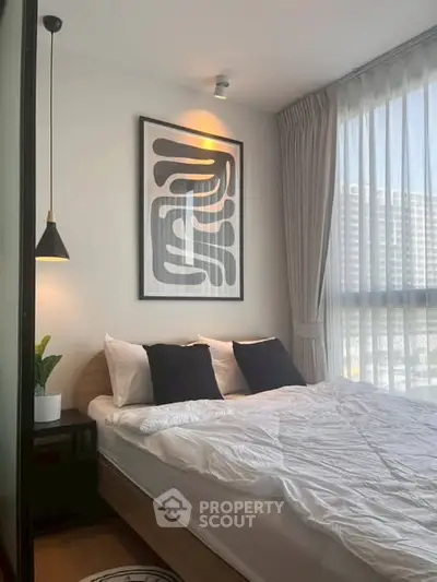 Modern bedroom with stylish decor and large window offering natural light.