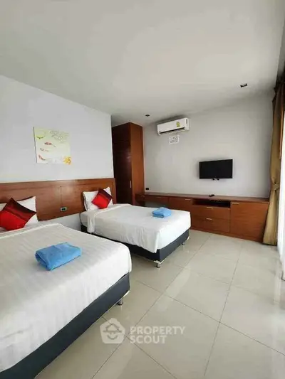 Modern bedroom with twin beds, air conditioning, and sleek wooden furniture.