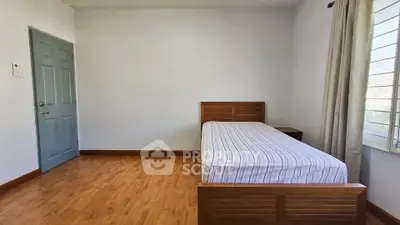 Minimalist bedroom with wooden flooring and single bed, perfect for cozy living.