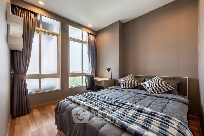 Modern bedroom with large windows and stylish decor in a cozy apartment.