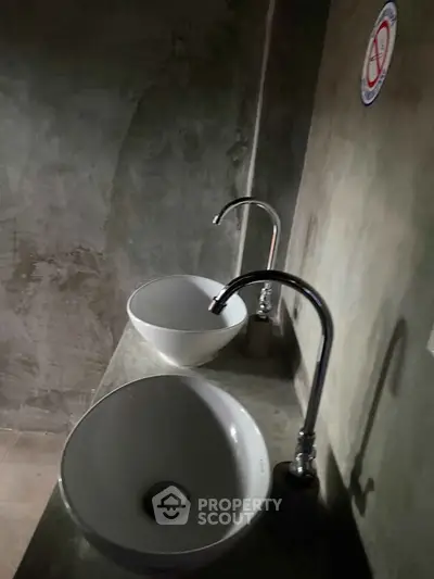 Modern minimalist bathroom with dual sinks and sleek faucets in concrete setting.