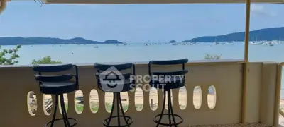 Stunning balcony view with bar stools overlooking serene ocean and distant islands.