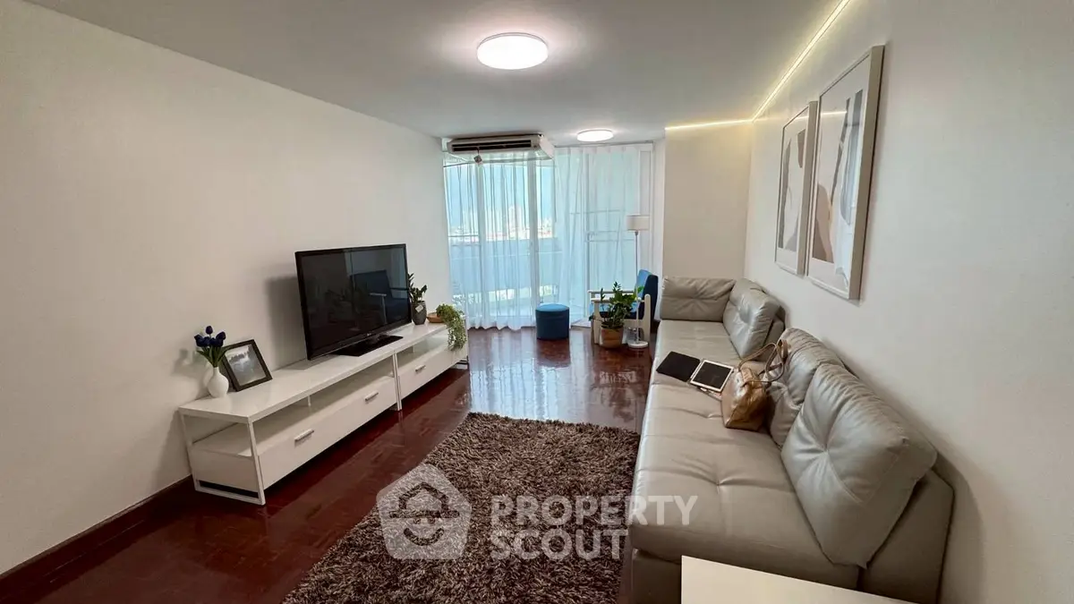 Spacious living room with modern decor and natural light, featuring a cozy seating area and entertainment center.