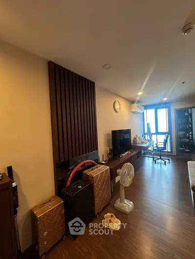 Spacious living room with modern decor and wooden flooring, featuring a TV and a large window for natural light.