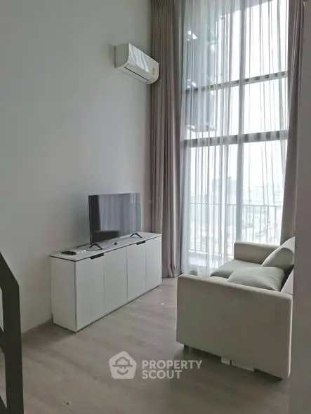 Modern living room with high ceilings, large windows, and minimalist furniture in a stylish apartment.