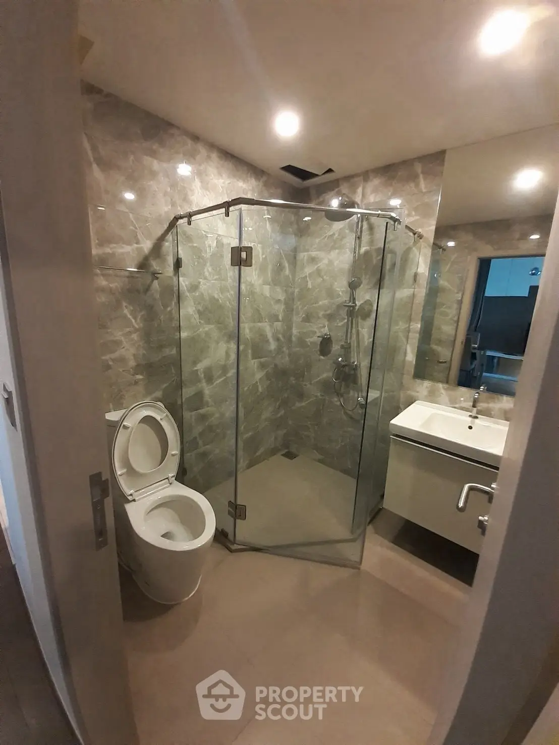 Modern bathroom with glass shower and marble walls in a contemporary apartment.
