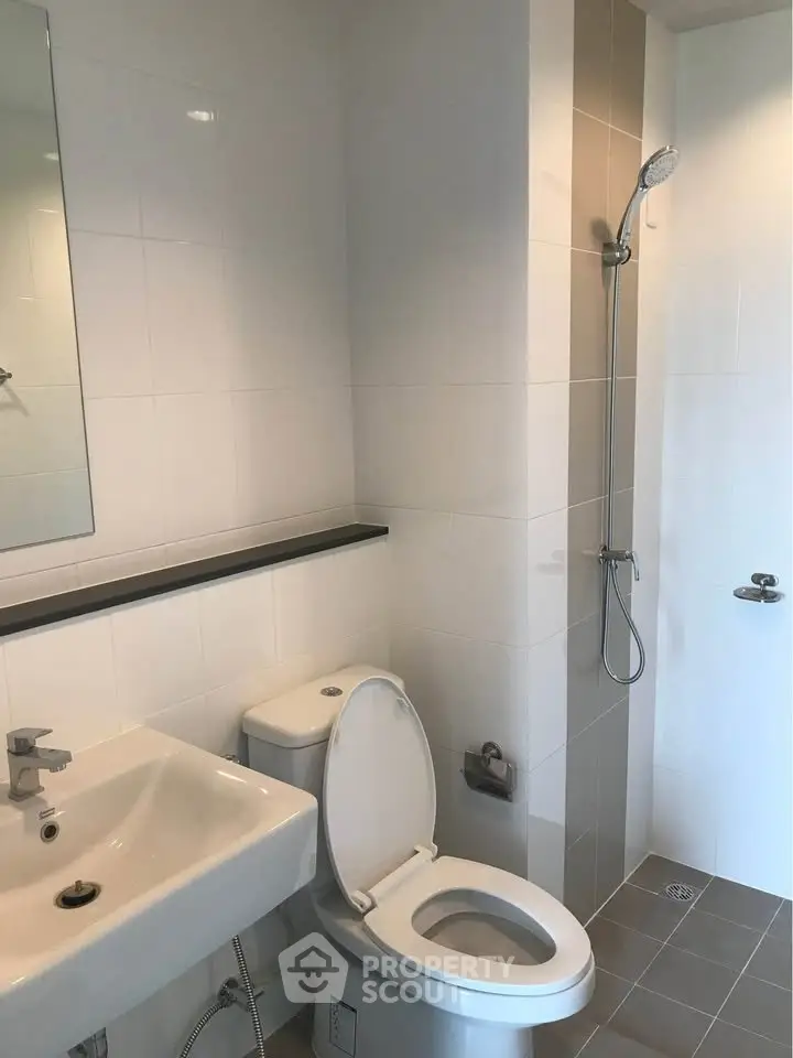 Modern bathroom with sleek fixtures and minimalist design, featuring a shower and toilet.