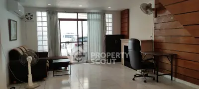 Spacious living room with modern decor and natural light, featuring a cozy sofa and desk area.