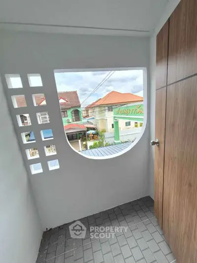 Charming balcony with unique window design and scenic neighborhood view.