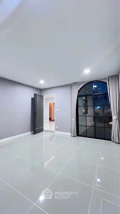 Spacious modern room with large window and glossy tiled floor