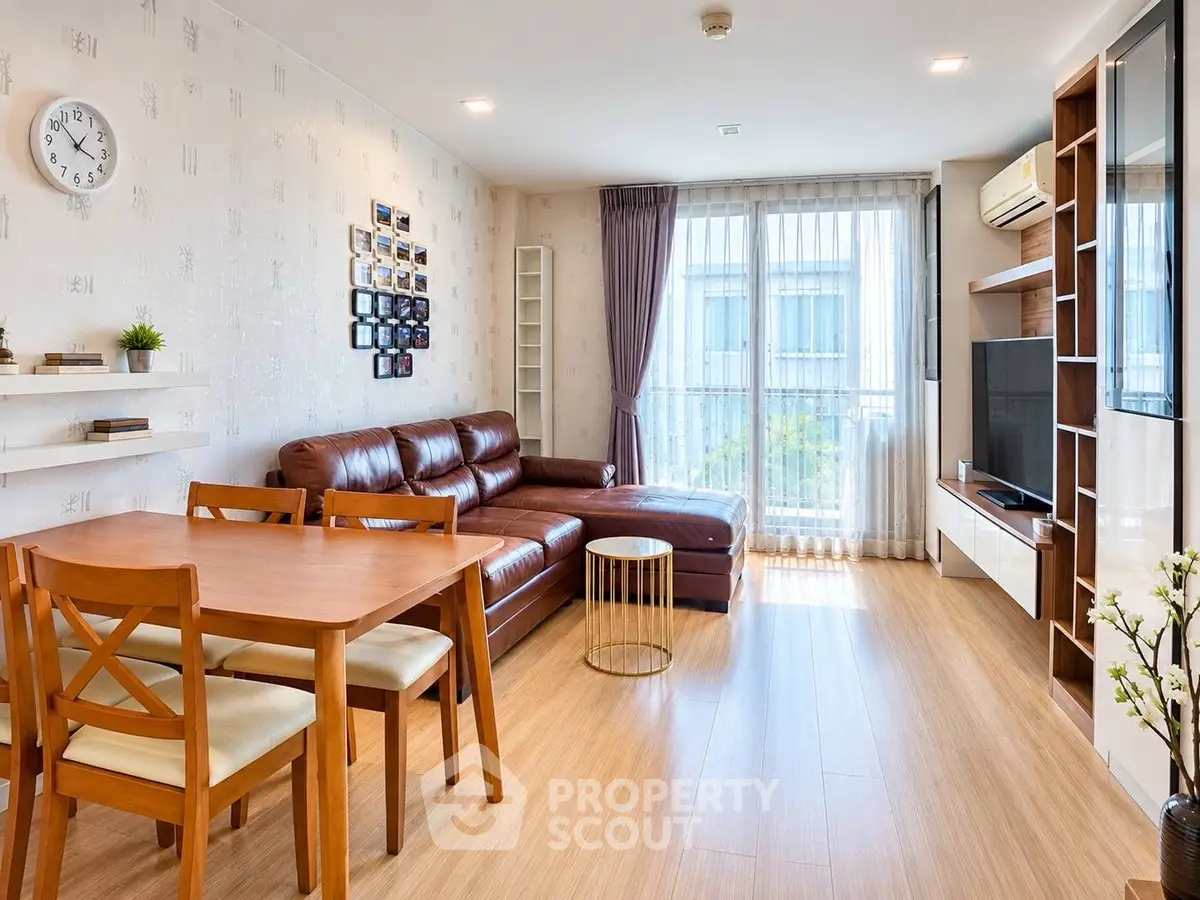 Modern living room with wooden flooring, leather sofa, and large window for natural light.