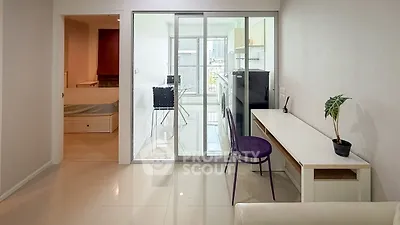 Modern apartment interior with sleek design and glass partition, featuring a cozy workspace and city view.