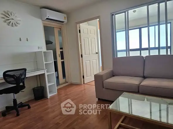 Modern living room with wooden flooring, cozy sofa, and study area with natural light.