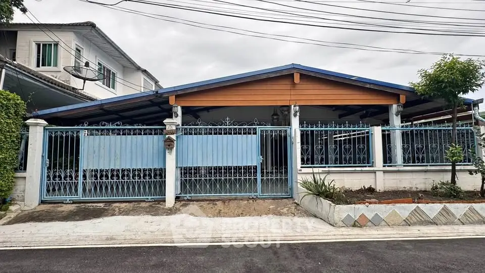 Charming single-story home with blue gated fence and manicured front garden, perfect for family living.
