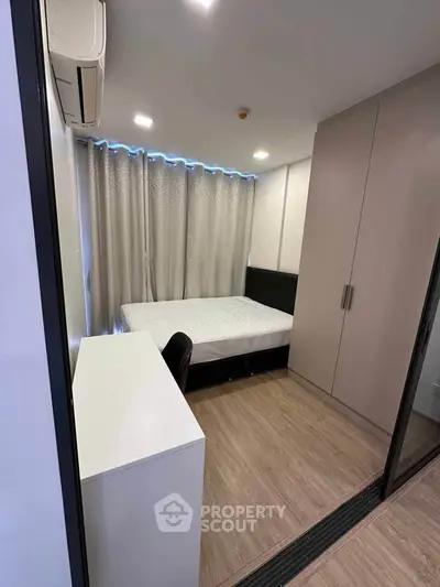 Modern bedroom with sleek design, featuring a comfortable bed, built-in wardrobe, and air conditioning.
