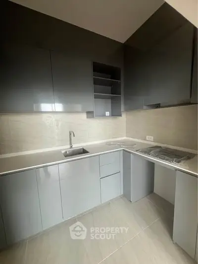 Modern kitchen with sleek gray cabinetry and integrated appliances in a contemporary apartment.