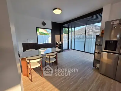 Modern kitchen with sleek design and natural light, featuring a dining area and large windows.