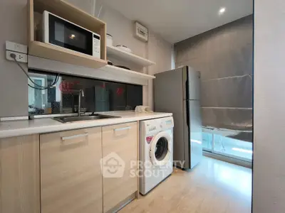 Modern kitchen with appliances including fridge, microwave, and washing machine in a sleek design.