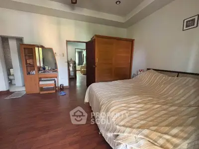 Spacious bedroom with wooden flooring and large wardrobe