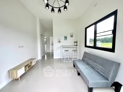 Modern living room with sleek furniture and large window offering scenic views.