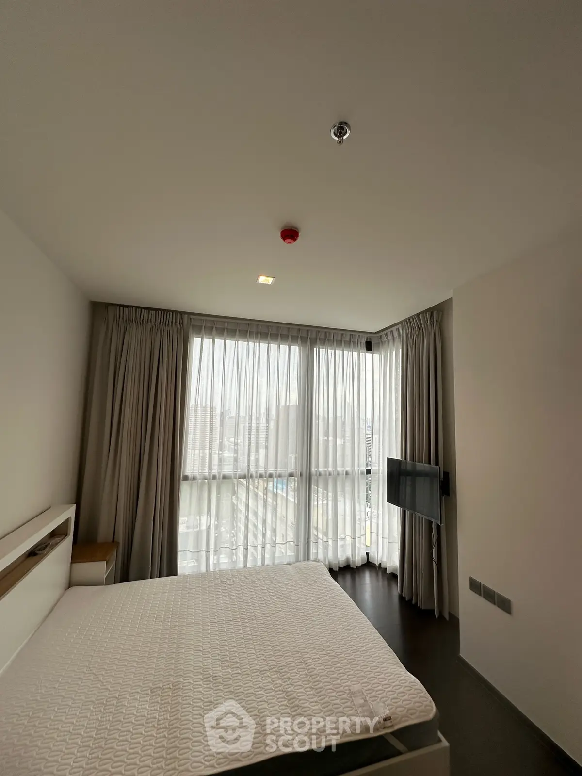 Modern bedroom with large windows and natural light in a stylish apartment.