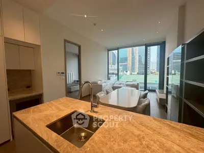 Modern open-plan kitchen and living room with city view, featuring sleek design and ample natural light.
