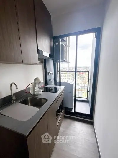 Modern compact kitchen with sleek cabinetry and balcony view, perfect for urban living.