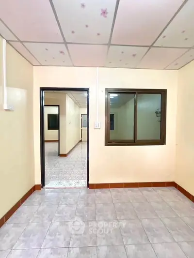 Bright and clean interior room with tiled flooring and window view