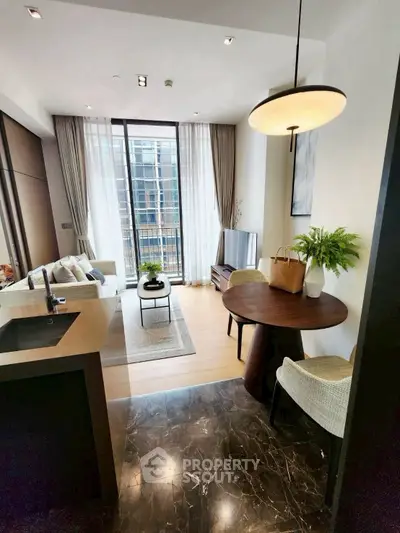 Modern living room with open kitchen, stylish decor, and large windows offering natural light.