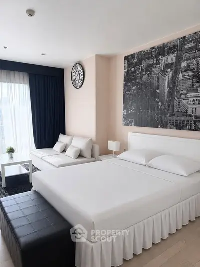 Modern bedroom with stylish decor and cityscape artwork, featuring a cozy seating area and large window.