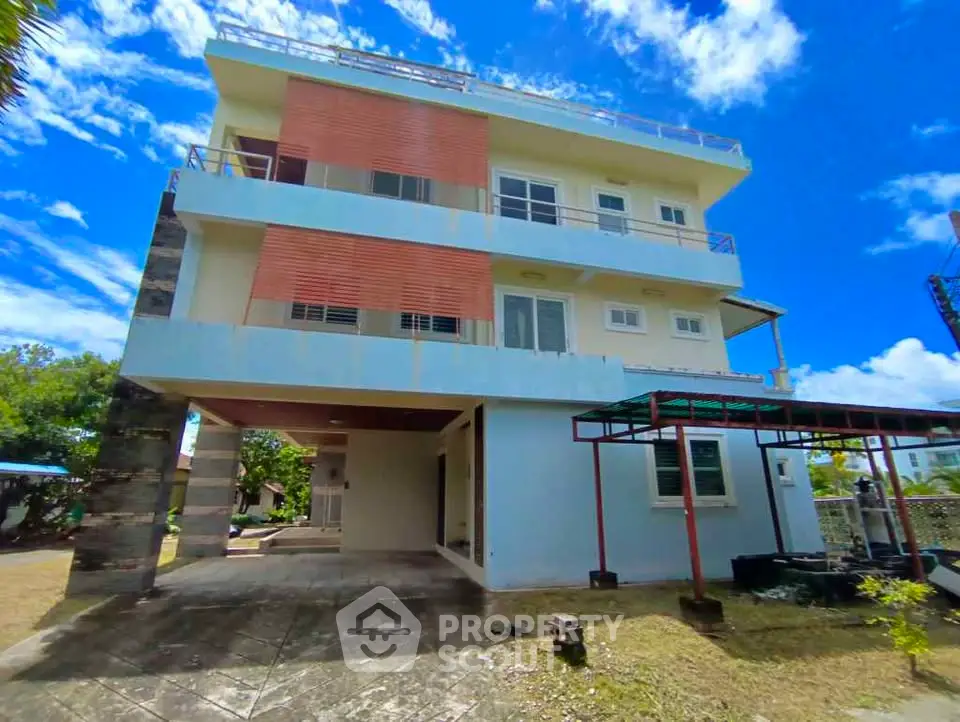 Modern multi-story building with spacious balconies and vibrant exterior under a clear blue sky.