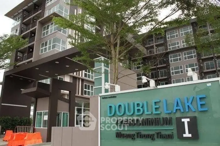 Modern condominium building with lush greenery and stylish entrance signage.