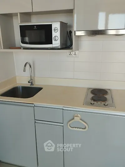 Modern kitchen with sleek cabinetry, electric stove, and microwave, perfect for compact living spaces.