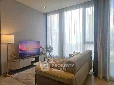 Modern living room with large windows, stylish furniture, and a flat-screen TV, perfect for relaxation.