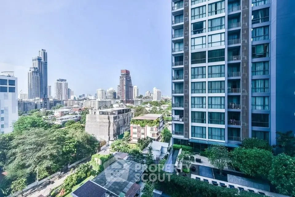 Stunning cityscape view from high-rise apartment with lush greenery and modern architecture.