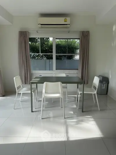 Modern dining area with sleek table and chairs, large window, and air conditioning unit.