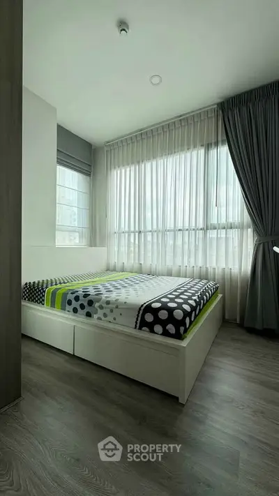 Modern bedroom with large windows and stylish decor in a contemporary apartment.