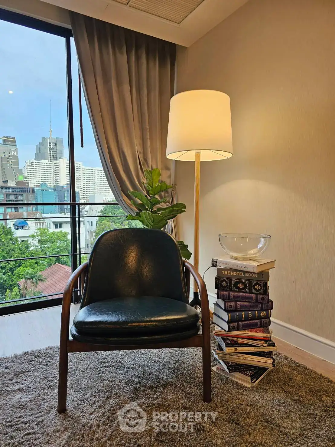 Chic urban living room with city view, stylish chair, and modern decor.