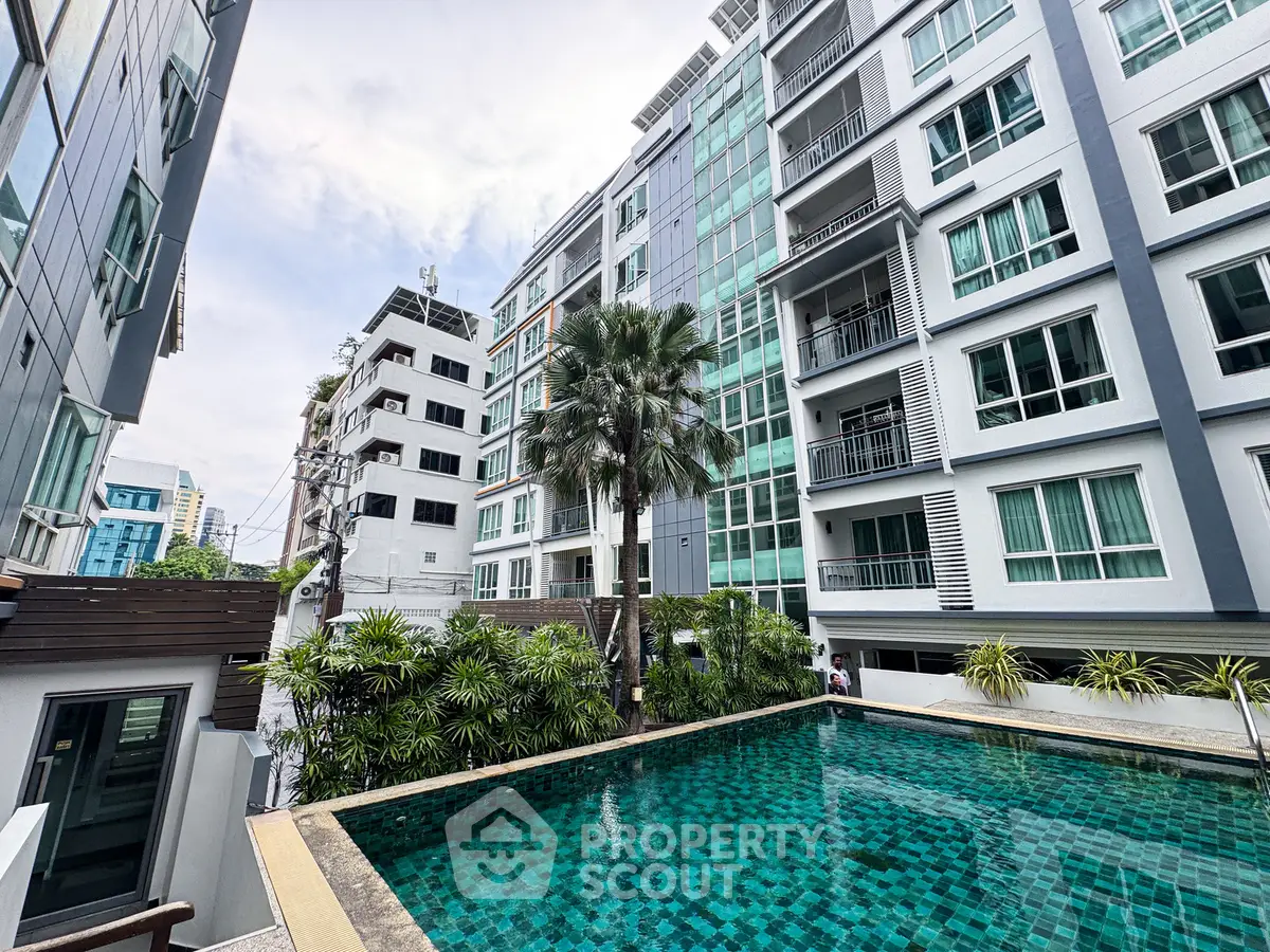 Modern condominium with a stunning pool and lush greenery, offering urban living with a touch of nature.