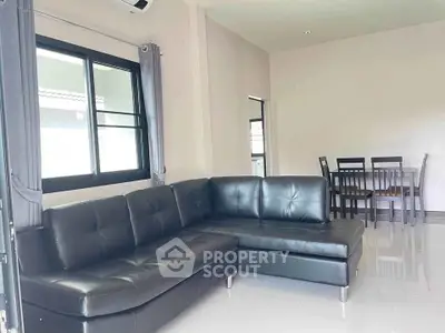 Modern living room with sleek black leather sectional and dining area, perfect for contemporary living.