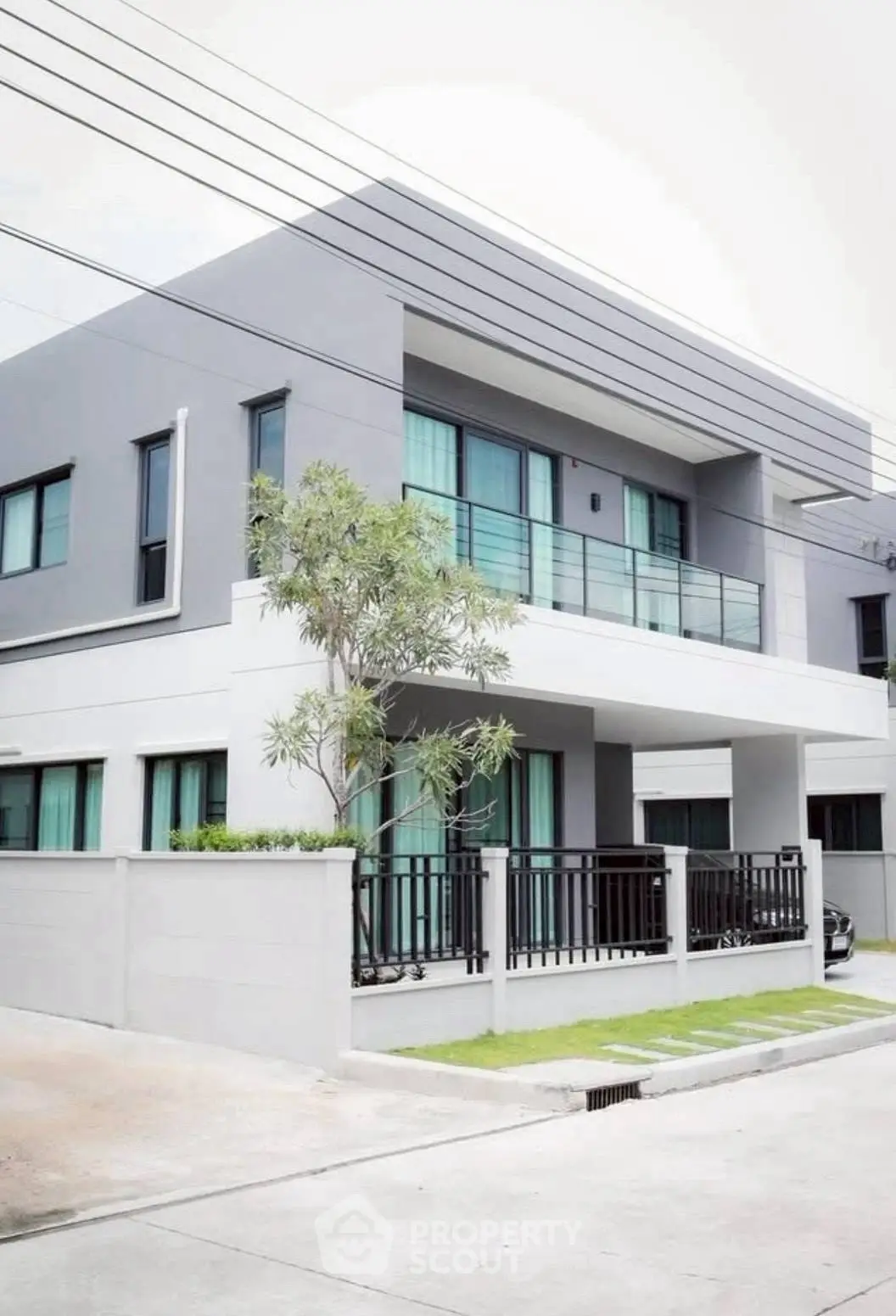 Modern two-story house with sleek design and large windows in a suburban neighborhood.