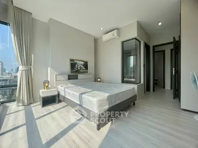 Modern bedroom with large windows and city view, featuring sleek design and ample natural light.