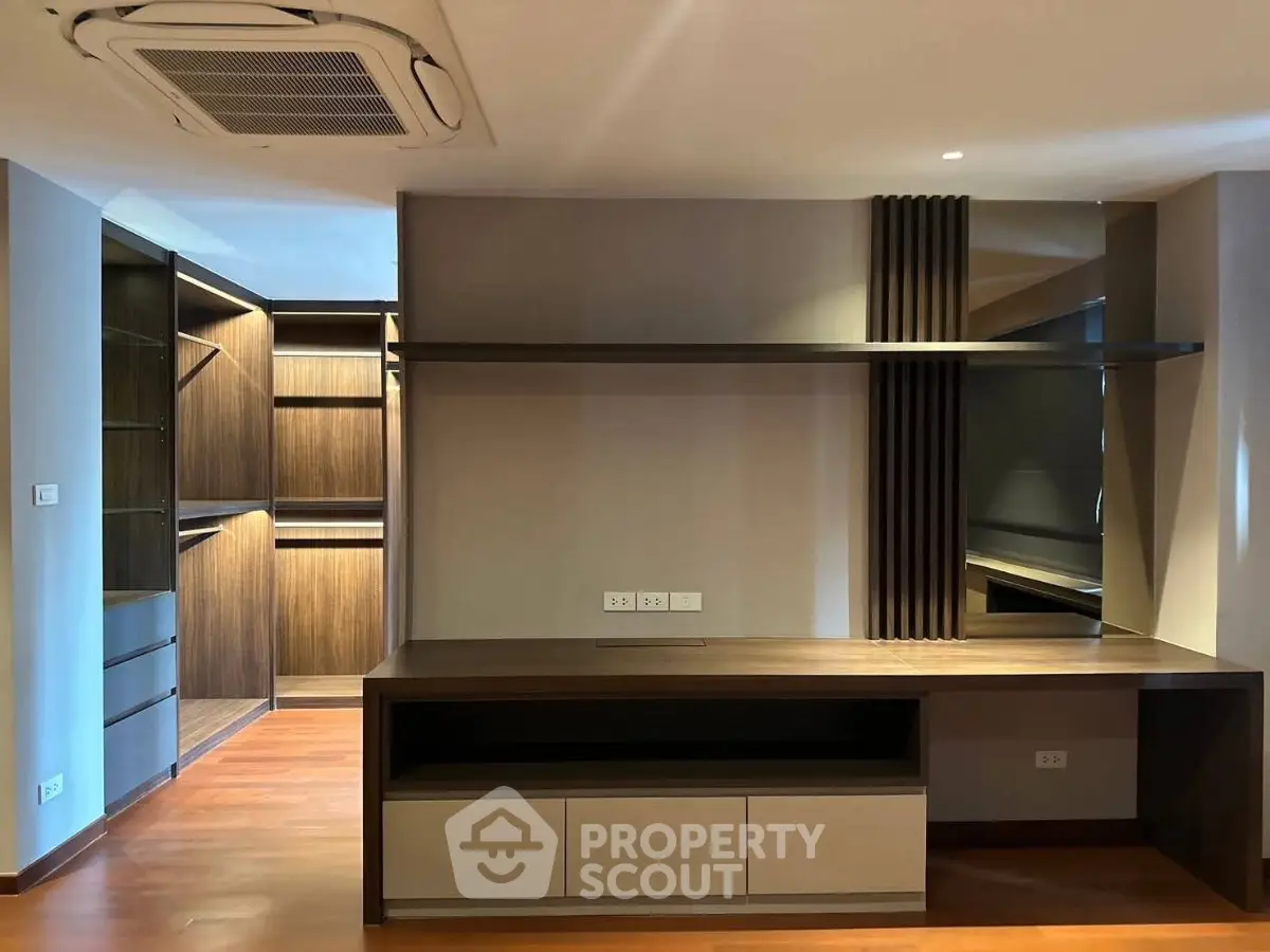Modern interior with built-in wooden shelves and desk, featuring sleek design and ample storage space.