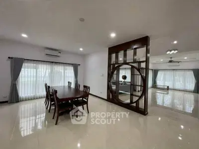 Spacious open-plan living and dining area with elegant wooden furniture and large windows.