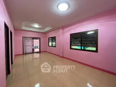 Spacious pink-walled room with large windows and tiled flooring, perfect for versatile living space.