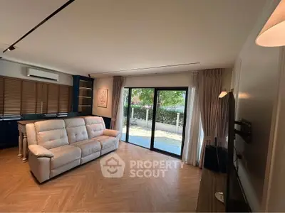 Spacious living room with modern decor and large sliding glass doors leading to a serene outdoor view.
