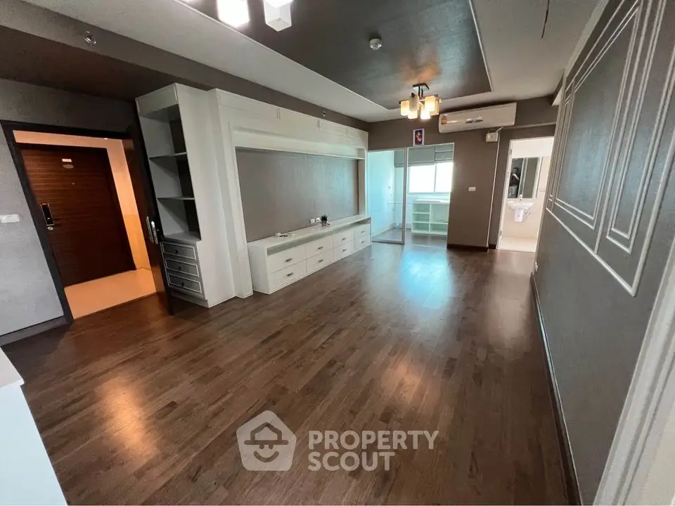 Spacious modern living room with hardwood floors and built-in storage in a stylish apartment.