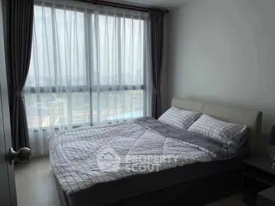 Modern bedroom with large window offering stunning city views and natural light.